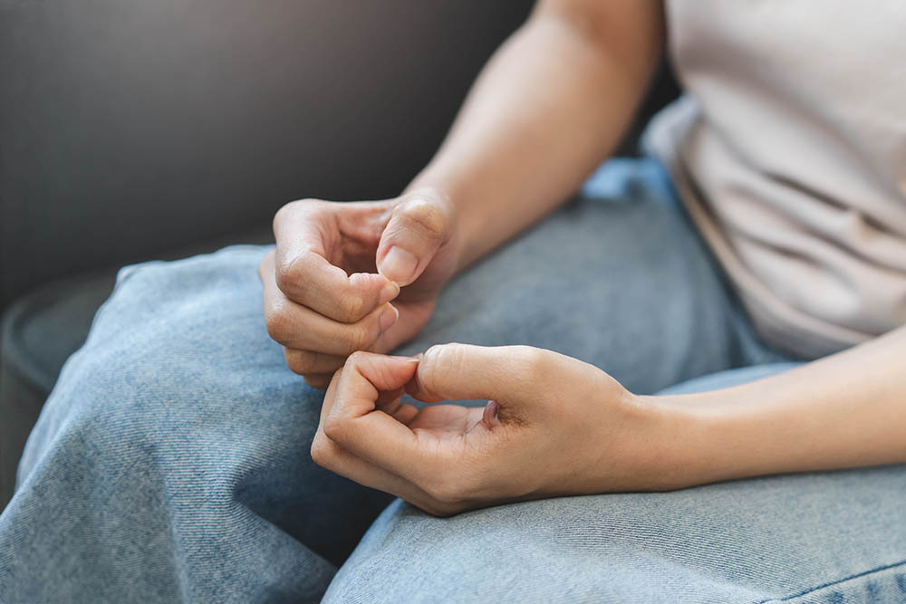Close up of an anxious woman sitting alone and nervously picking